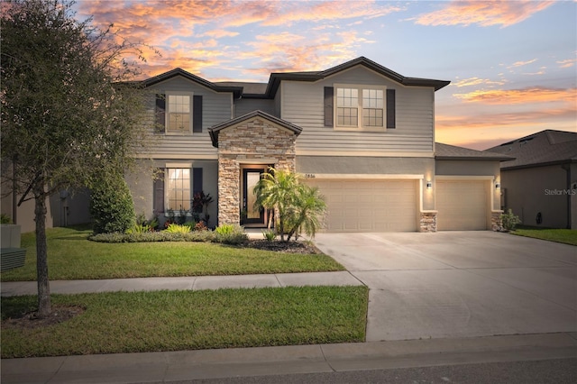 traditional home with a yard, stucco siding, concrete driveway, a garage, and stone siding