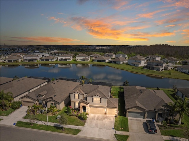 aerial view at dusk featuring a residential view and a water view