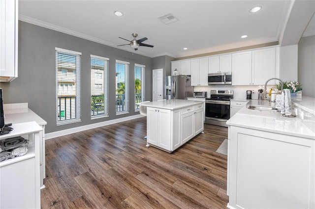 kitchen featuring dark wood-style floors, visible vents, a sink, ornamental molding, and stainless steel appliances