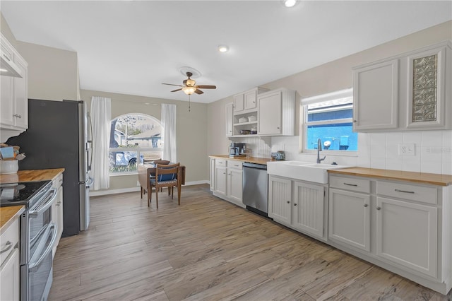 kitchen featuring stainless steel appliances, butcher block countertops, light wood-style flooring, and decorative backsplash