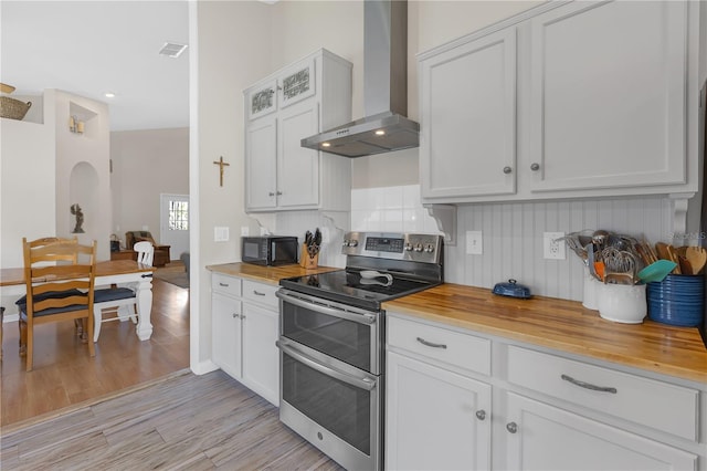 kitchen featuring wooden counters, double oven range, black microwave, and wall chimney range hood