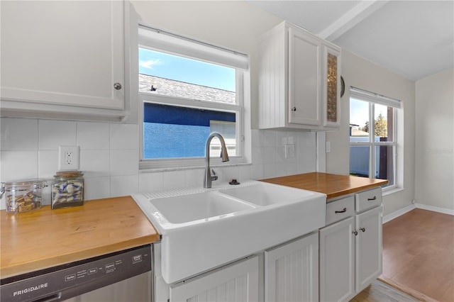 kitchen featuring tasteful backsplash, wooden counters, stainless steel dishwasher, white cabinets, and a sink