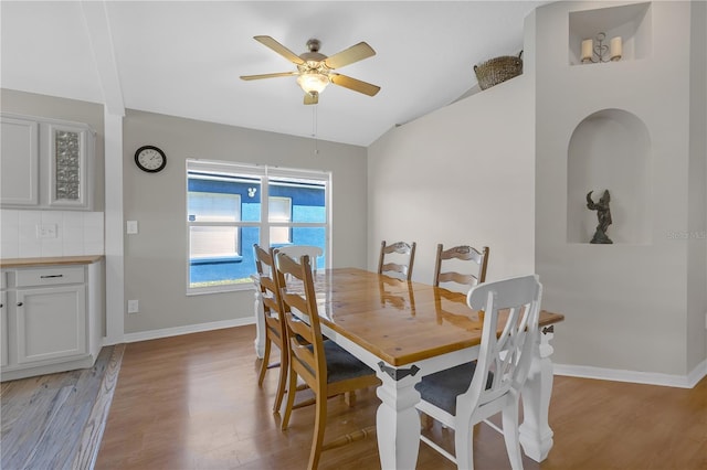 dining room with baseboards, lofted ceiling, and light wood-style floors