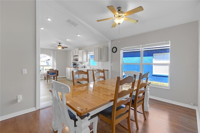 dining space featuring a ceiling fan, baseboards, visible vents, and light wood finished floors