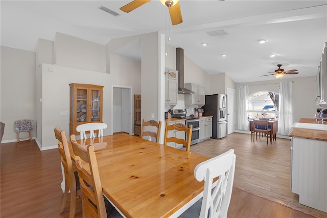 dining room featuring visible vents, high vaulted ceiling, light wood-style flooring, a ceiling fan, and baseboards