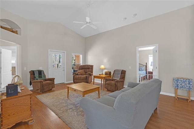 living area featuring high vaulted ceiling, baseboards, light wood-style floors, and a ceiling fan