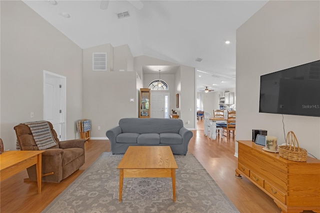 living area featuring high vaulted ceiling, visible vents, light wood-style floors, and a ceiling fan