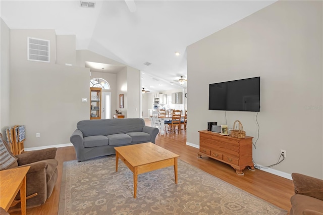 living area featuring lofted ceiling, wood finished floors, and visible vents