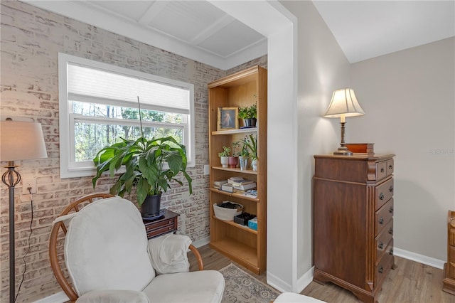 sitting room with baseboards, wood finished floors, and brick wall