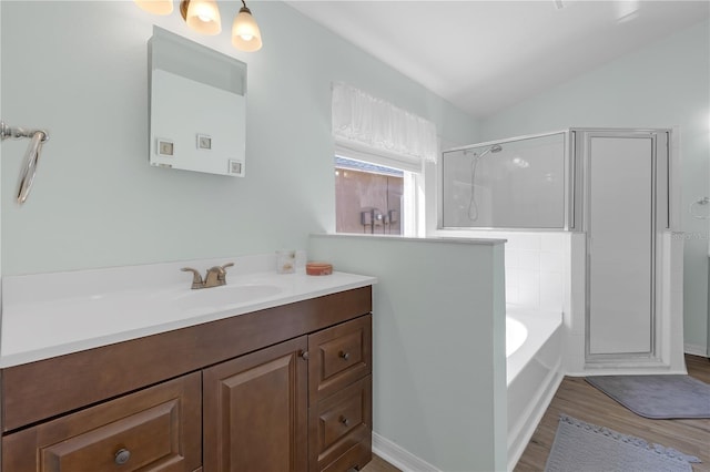 full bathroom featuring a garden tub, wood finished floors, a shower stall, vanity, and vaulted ceiling