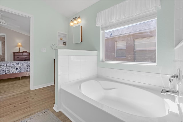 ensuite bathroom featuring connected bathroom, baseboards, a garden tub, and wood finished floors