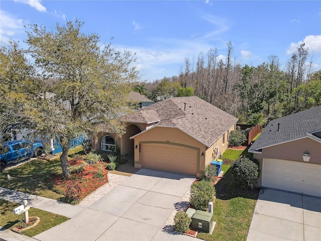 view of front of property with stucco siding, a front lawn, roof with shingles, concrete driveway, and a garage