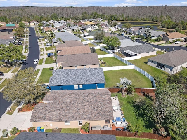 drone / aerial view with a residential view, a wooded view, and a water view