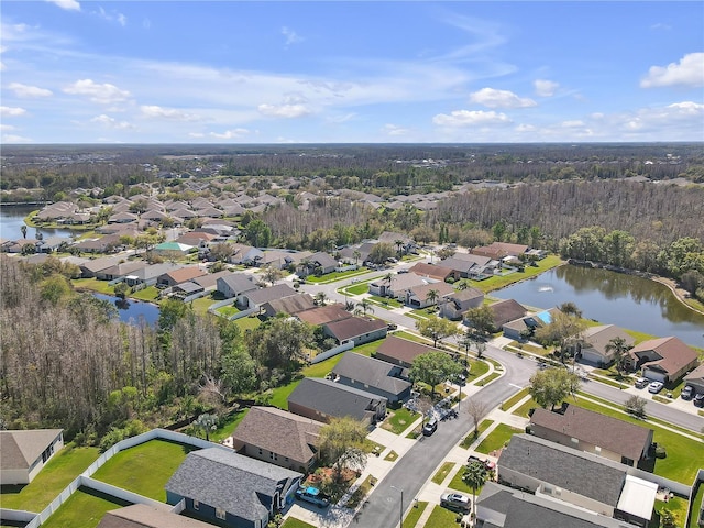 aerial view featuring a wooded view, a water view, and a residential view