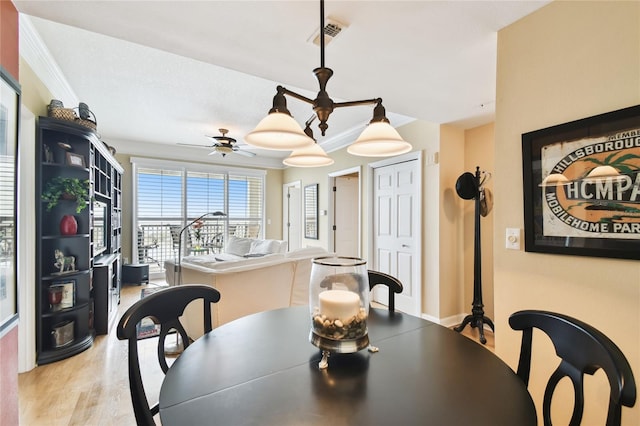 dining area with visible vents, crown molding, ceiling fan, and wood finished floors