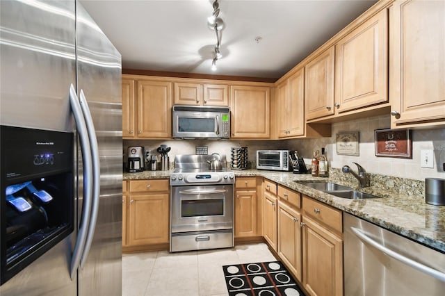 kitchen with a sink, backsplash, stainless steel appliances, a toaster, and light tile patterned floors