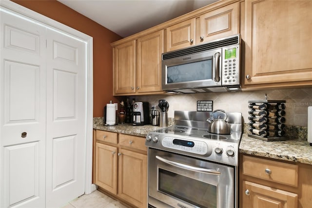 kitchen featuring light stone counters, backsplash, appliances with stainless steel finishes, and light tile patterned flooring