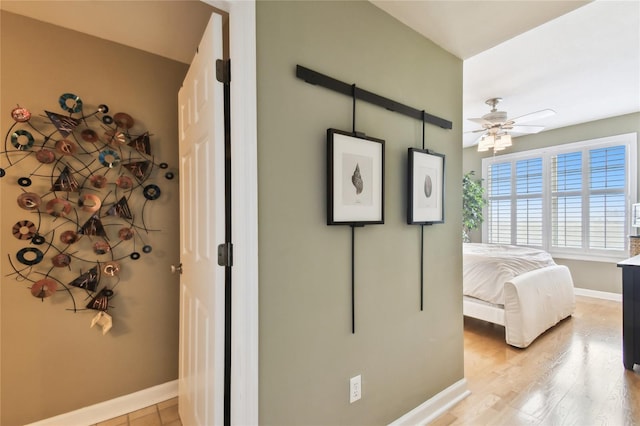 bedroom with ceiling fan, light wood-style floors, and baseboards