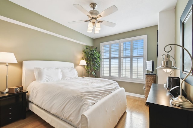 bedroom featuring baseboards, light wood-style floors, and ceiling fan