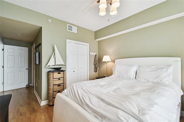 bedroom featuring visible vents, baseboards, wood finished floors, a closet, and a ceiling fan