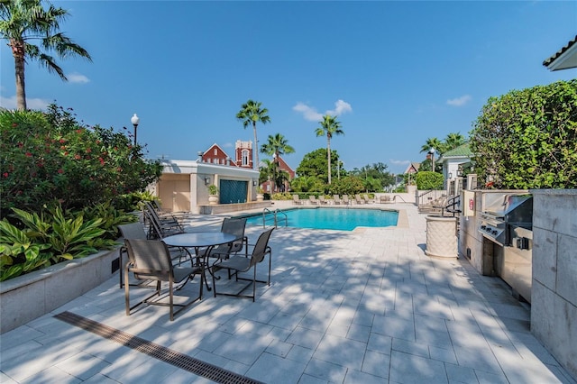 pool with grilling area and a patio area