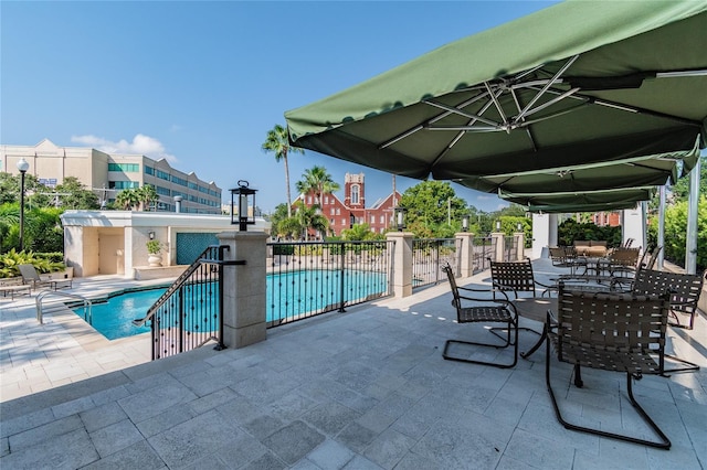 view of patio featuring outdoor dining area, a community pool, and fence