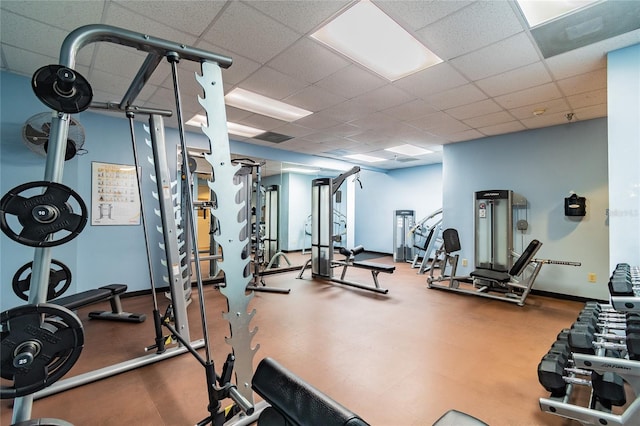 gym with a drop ceiling and baseboards