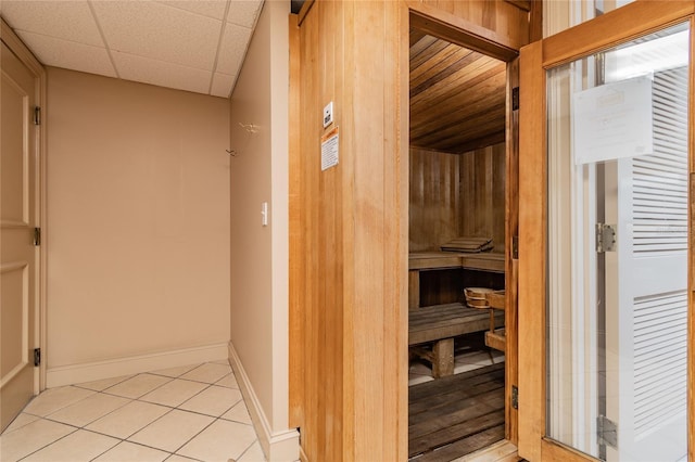 corridor featuring light tile patterned floors, a drop ceiling, a sauna, and baseboards