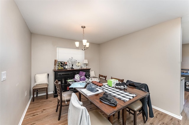 dining room with light wood-style flooring, baseboards, and an inviting chandelier