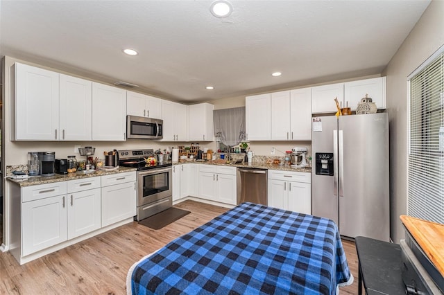 kitchen featuring light stone counters, recessed lighting, light wood-style flooring, white cabinets, and stainless steel appliances