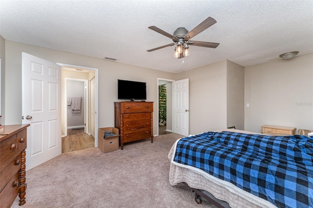 carpeted bedroom featuring a ceiling fan, visible vents, and a textured ceiling