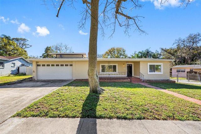 view of front of property featuring driveway, a front lawn, fence, covered porch, and an attached garage