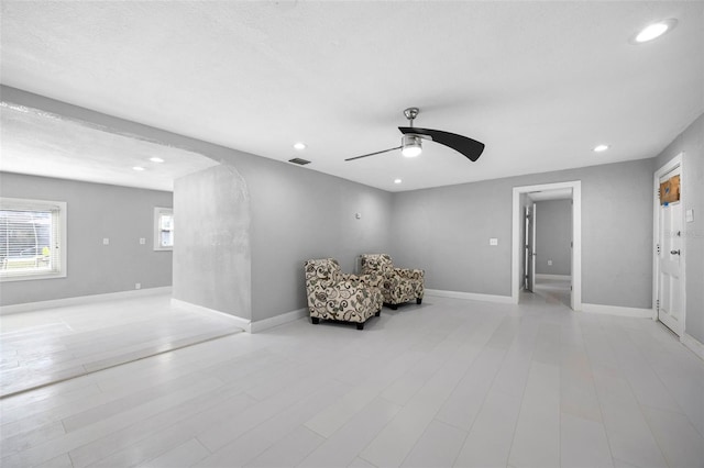 living area with a ceiling fan, baseboards, light wood finished floors, recessed lighting, and arched walkways