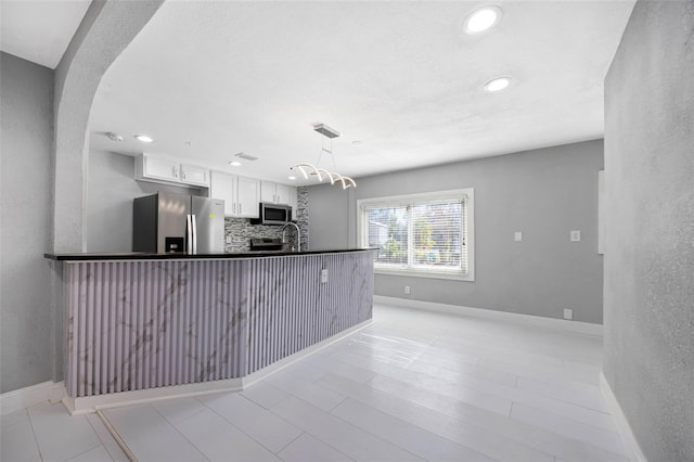 kitchen featuring decorative backsplash, appliances with stainless steel finishes, white cabinetry, and baseboards