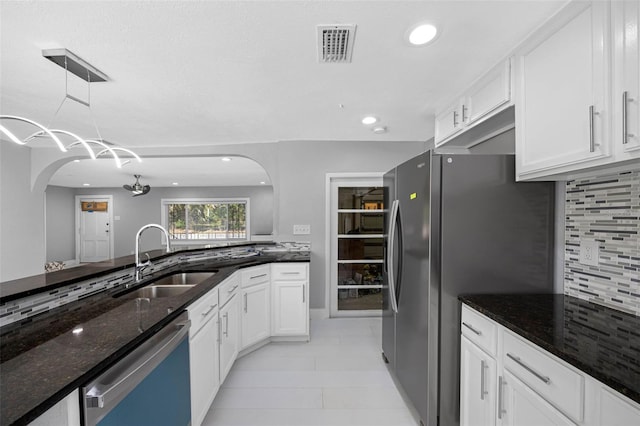 kitchen featuring a sink, white cabinetry, freestanding refrigerator, dark stone counters, and dishwashing machine