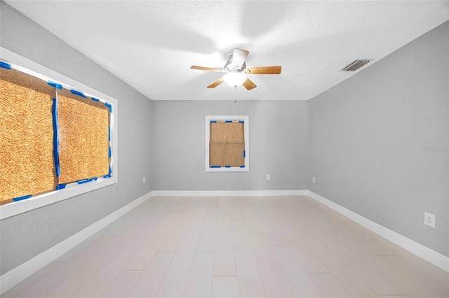 unfurnished room with visible vents, ceiling fan, baseboards, wood finished floors, and a textured ceiling