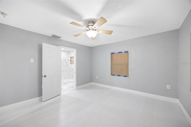 spare room with visible vents, baseboards, a textured ceiling, and a ceiling fan