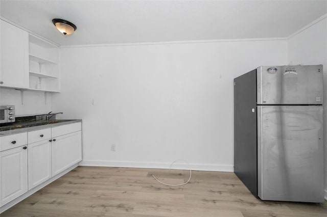 kitchen with ornamental molding, open shelves, white cabinetry, freestanding refrigerator, and light wood finished floors