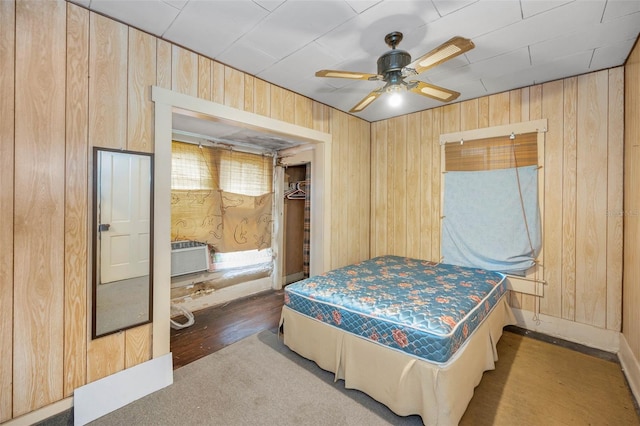 bedroom with wooden walls, an AC wall unit, and a ceiling fan