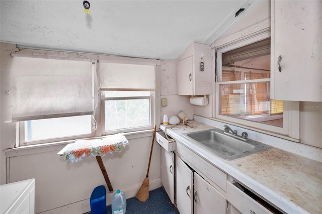 kitchen featuring vaulted ceiling, white cabinets, light countertops, and a sink