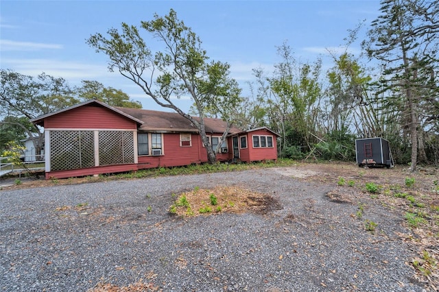rear view of property with cooling unit and gravel driveway
