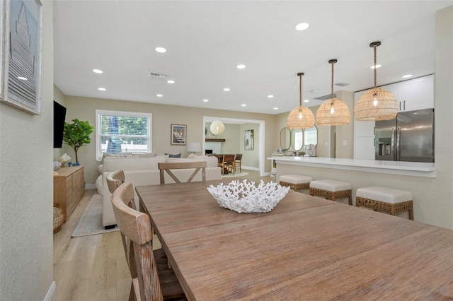 dining space with a fireplace, recessed lighting, visible vents, and light wood-type flooring