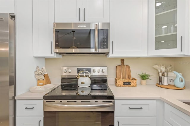 kitchen featuring white cabinetry, light countertops, glass insert cabinets, and stainless steel appliances