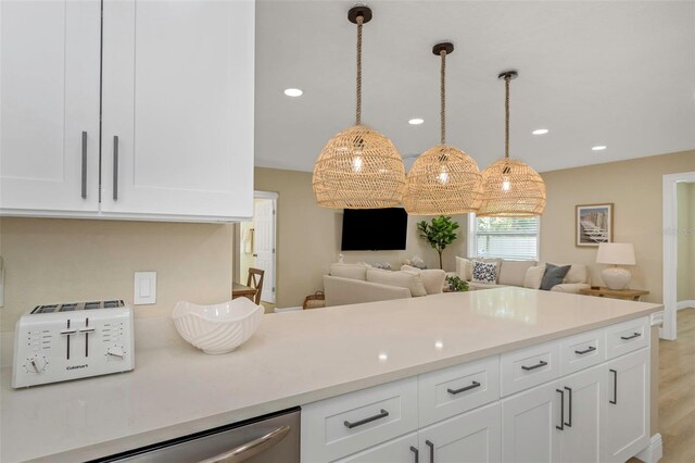 kitchen with stainless steel dishwasher, open floor plan, light countertops, and white cabinetry