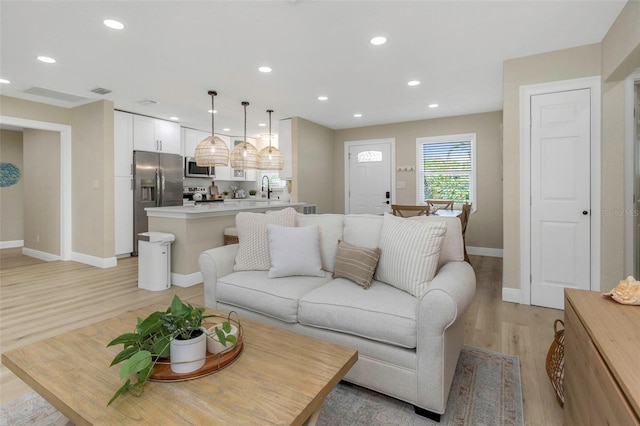 living area with recessed lighting, light wood-style floors, and baseboards