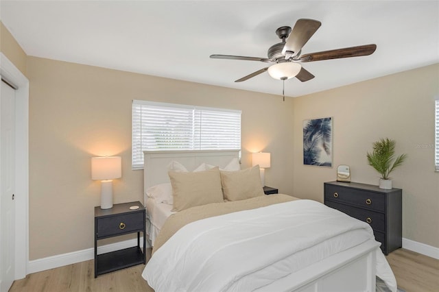 bedroom featuring baseboards, light wood-style floors, and a ceiling fan