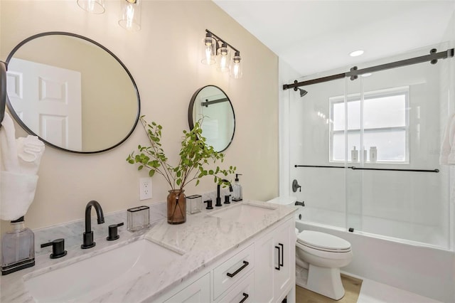 bathroom featuring double vanity, enclosed tub / shower combo, toilet, and a sink