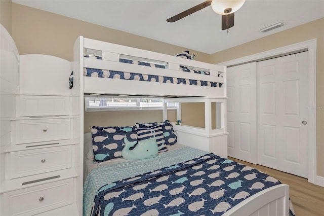 bedroom with light wood-type flooring, visible vents, a closet, and a ceiling fan