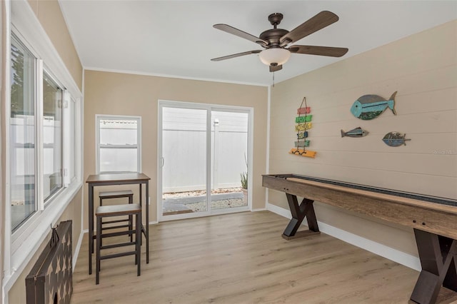 interior space with crown molding, light wood-style flooring, baseboards, and ceiling fan