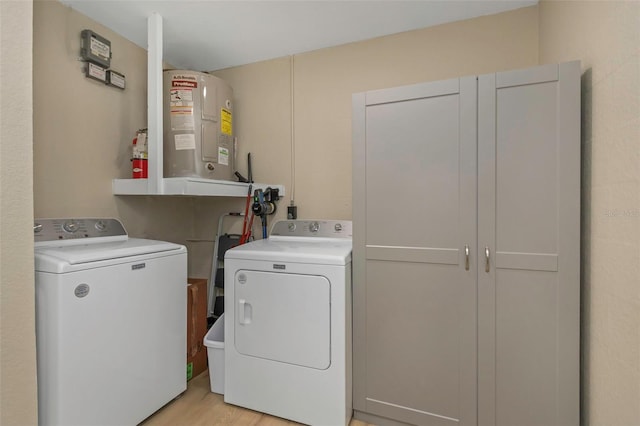 washroom with cabinet space, separate washer and dryer, water heater, and light wood-type flooring